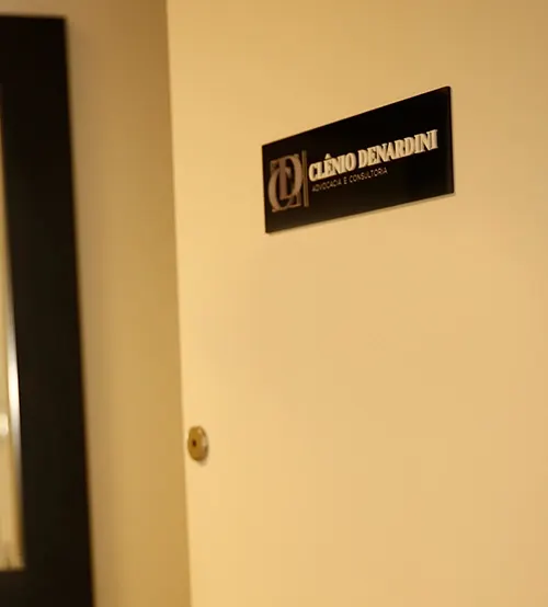 Placa com o logo Clênio Denardini na porta da sala
