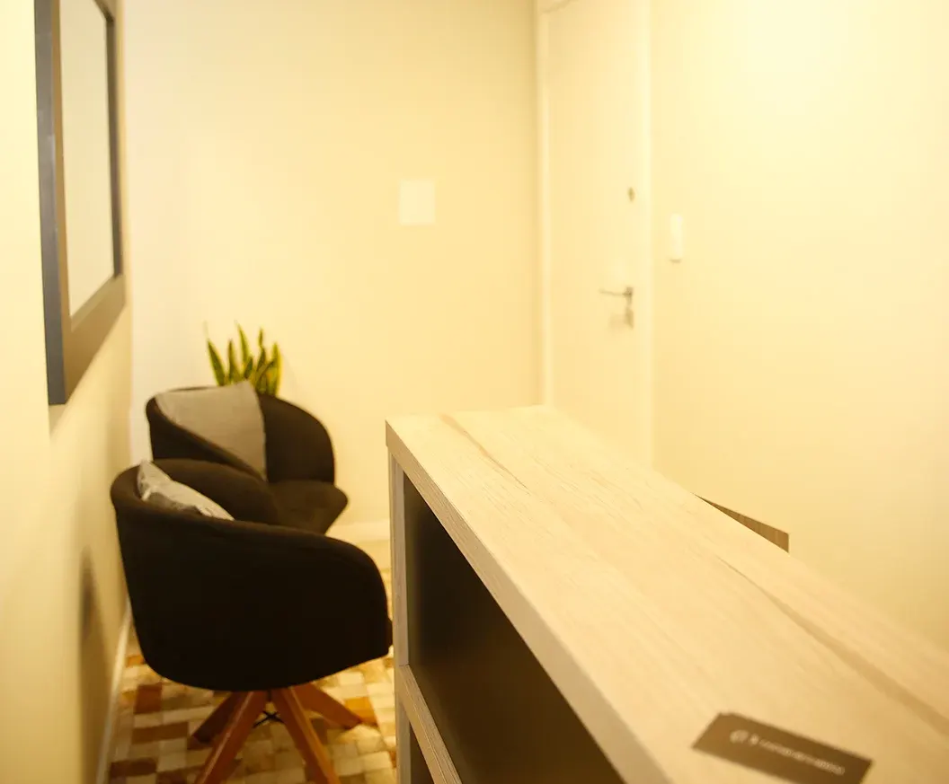 Recepção do escritório, com poltrona, planta e balcão claro